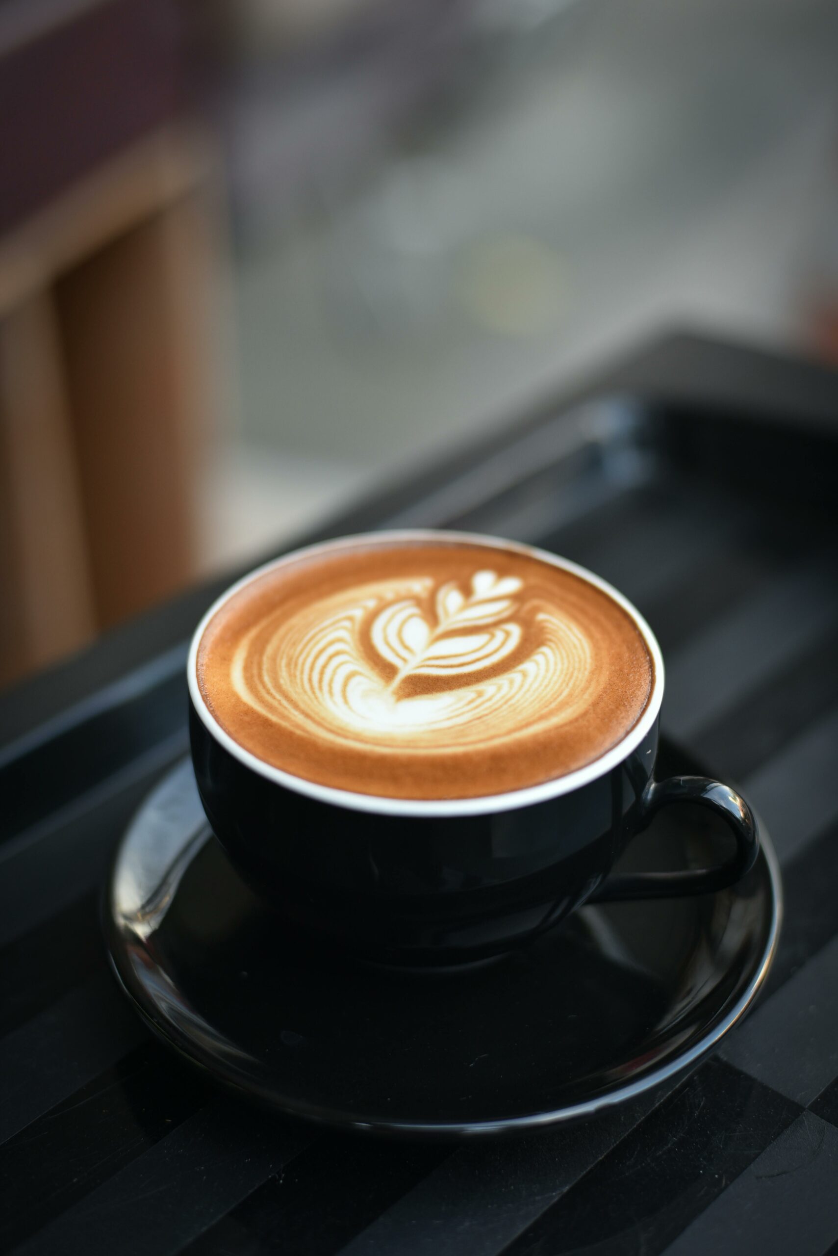 pexels-photo-312418-312418 A beautifully crafted cappuccino with intricate latte art in a black ceramic mug on a dark surface.
