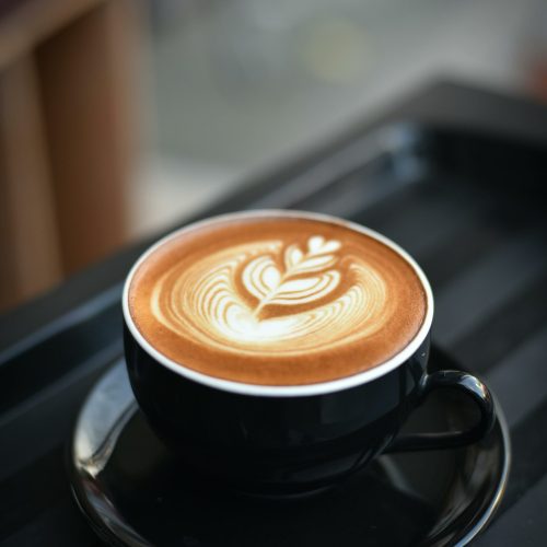 pexels-photo-312418-312418 A beautifully crafted cappuccino with intricate latte art in a black ceramic mug on a dark surface.